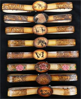 Collection of handcrafted leather belts for kids with intricate carvings and engraved buckles featuring wildlife, floral, and Western themes.